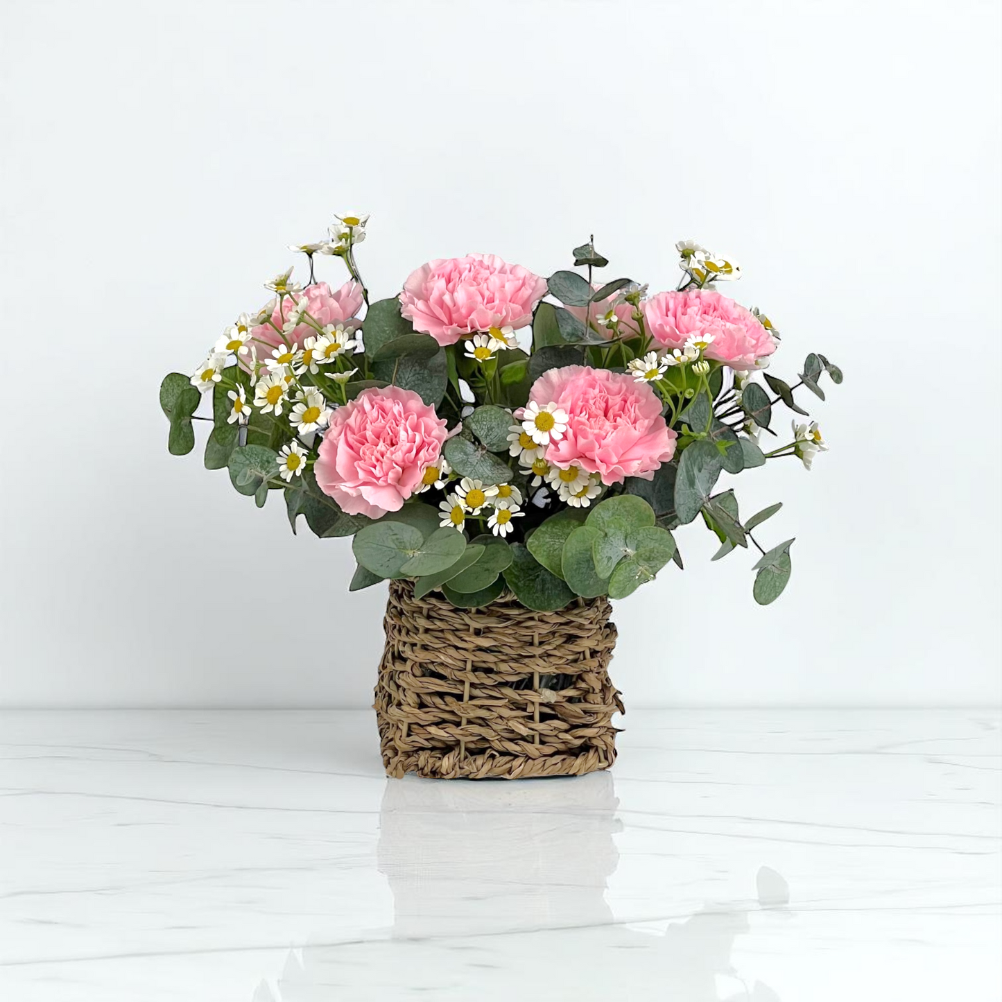 Close-up of Sweet Whisper basket with pink carnations and chamomile, ideal as a gentle and comforting flower gift.