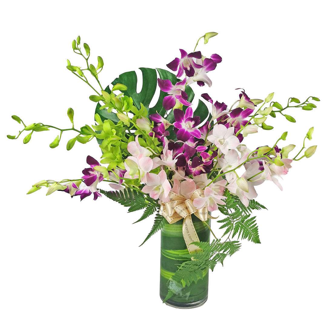 Pink and purple fresh orchid table flower arrangement in straight glass vase filled with water
