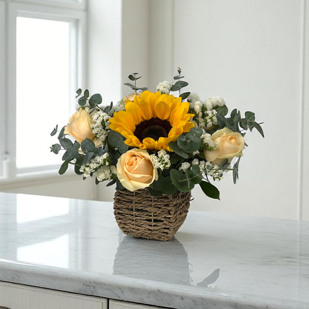 Front view of Golden Shine flower basket with bright sunflowers and peach roses, arranged in a compact decorative basket.