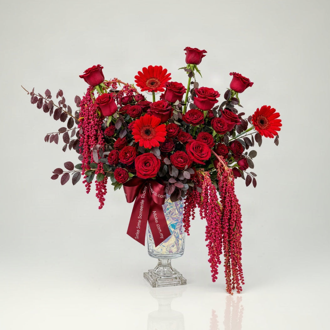 Velvet Royale table flower arrangement with red roses, red spray roses, red gerberas and hanging amaranthus in a glass chalet vase