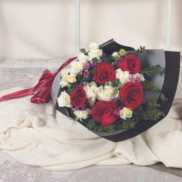 Mind Renewed flower bouquet with red roses, white blooms, pink accents and lush greenery, wrapped in black paper