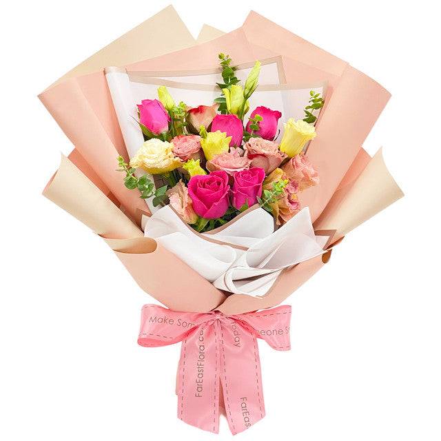 Premium Roses bouquet with pink, peach and cream blooms, delicate flowers and green foliage in layered wrapping.Ribbon bow