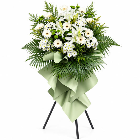 Everlasting Peace condolence flower stand with white lilies, white gerberas, white and green pom poms and yellow peacock flowers