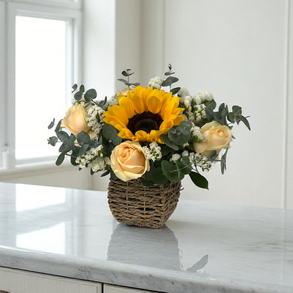 Front view of Golden Shine flower basket with bright sunflowers and peach roses, arranged in a compact decorative basket.
