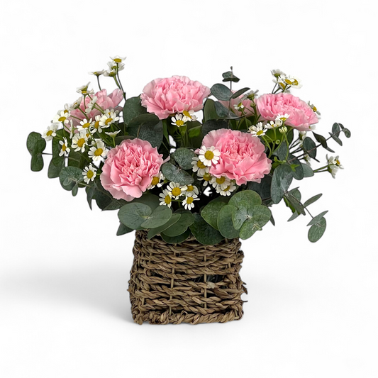 Front view of Sweet Whisper flower basket featuring soft pink carnations and fresh chamomile in a small, charming arrangement.