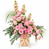 Rosie Embrace table flower arrangement with light pink roses, peach spray roses, pink carnations and champagne matthiola in a blush pink holder with gold ribbon
