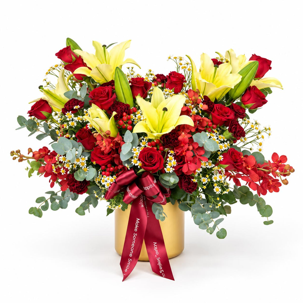 Crimson Glow table flower arrangement with red roses, yellow lilies, maroon carnations, mokara orchids and chamomile in a gold container