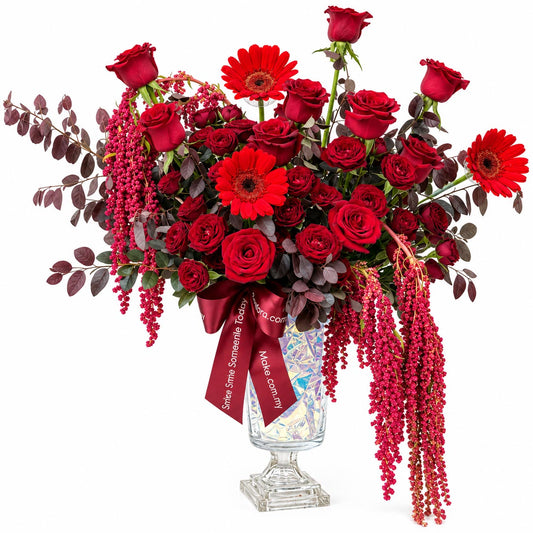 Velvet Royale table flower arrangement with red roses, red spray roses, red gerberas and hanging amaranthus in a glass chalet vase